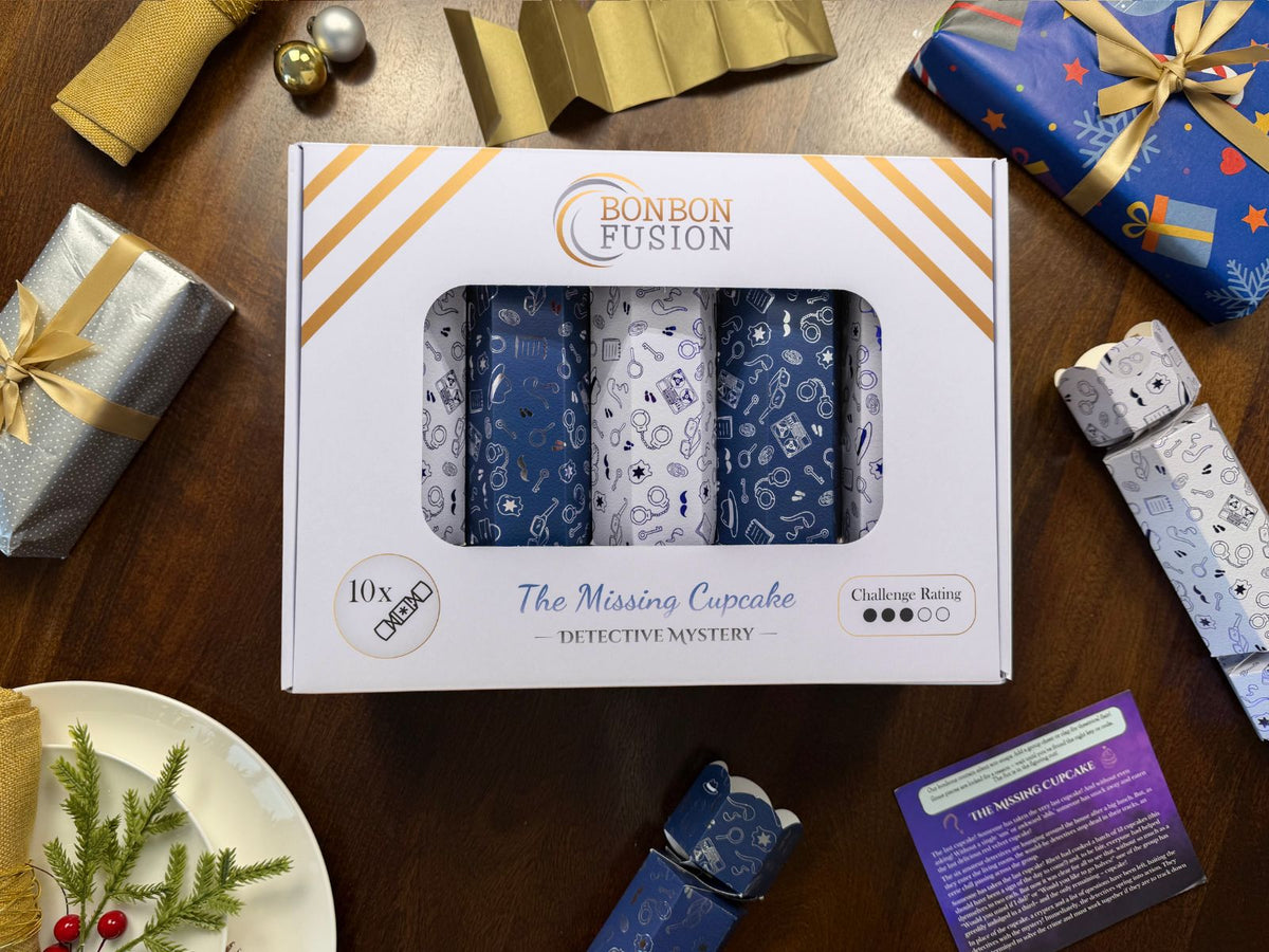 Bonbon Fusion The Missing Cupcake Detective Mystery pack of ten navy and white Christmas bonbons on a festive dinner table, with a gold paper crown, two single bonbons and "The Missing Cupcake" mystery story card
